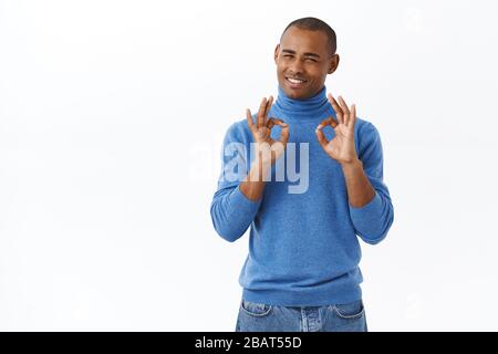 Portrait of pleased handsome african-american man showing okay sign, guarantee best quality, being satisfied with perfect service, describing amazing Stock Photo