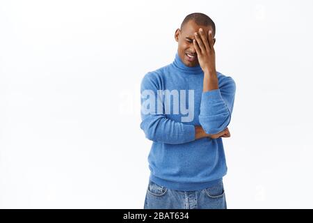 Portrait of distressed, sad young grieving african-american man facepalm, sobbing and grimacing as facing terrible proble, standing uneasy depressed Stock Photo