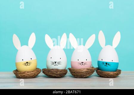 Easter eggs with bunny faces in nest on a blue background with space for copy Stock Photo