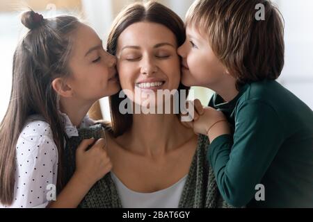 Loving little kids siblings kissing cheeks of affectionate young mommy. Stock Photo