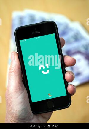 A woman using the Chip savings app on a mobile phone. (Editorial Use Only) Stock Photo