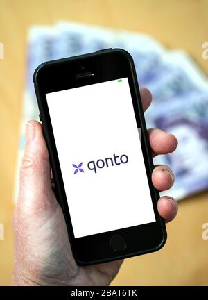 A woman using the qonto business banking app on a mobile phone. (Editorial Use Only) Stock Photo