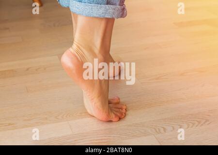 Close up focus on young female feet walking barefoot on clean wooden floor Stock Photo