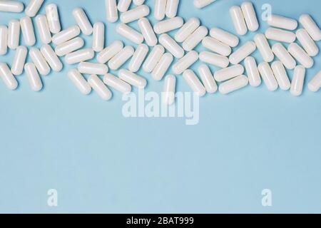 White medical pills on blue background with copy space Stock Photo