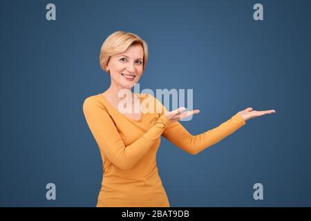 Middle aged woman pointing with palm hands aside Stock Photo