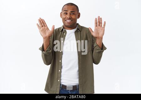 Sorry, dont mind me. Portrait of awkward and embarrassed african-americna man, apologizing, raising hands in surrender and smiling, interrupted Stock Photo