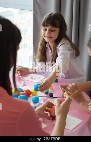Happy child paints Easter eggs with his family Stock Photo