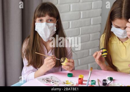 A sick quarantined child paints Easter eggs for the holiday Stock Photo