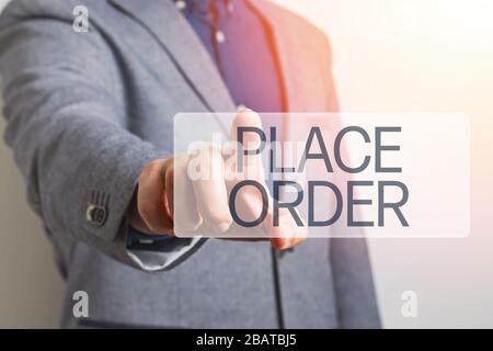 Man's hand with point finger pushing virtual online button with text Place Order close-up. Stock Photo