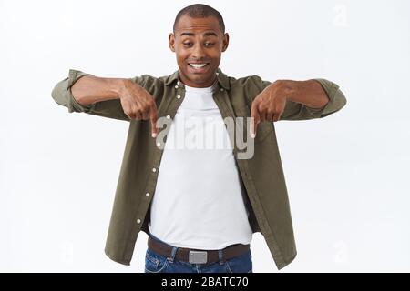 Portrait of cheerful, excited happy man, african american male pointing down, seeing good offer, special discount, finally found good deal, standing Stock Photo