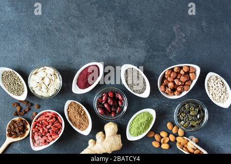 Small white bowls with various superfoods on black background top view. Healthy eating concept. Copy space. Stock Photo