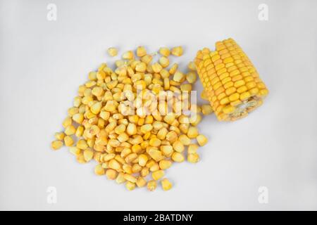 Fresh and delicious ear of sweet yellow corn and some corn seeds on an isolated white background Stock Photo