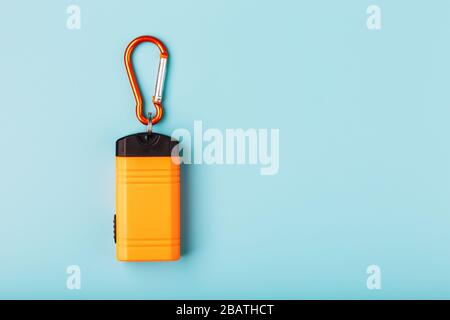 Orange led Flashlight with a carabiner on a blue background. LED lights in flight. Stock Photo