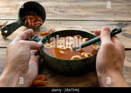 Red tomato soup with shrimp. Dish with tomatoes and prawns. Hands and food. Stock Photo