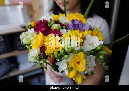 Shallow depth of field image (selective focus) with a woman holding a fresh bouquet of freesias. Stock Photo