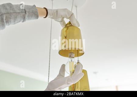 Hands installing LED bulb in lamp, chandelier. Stock Photo