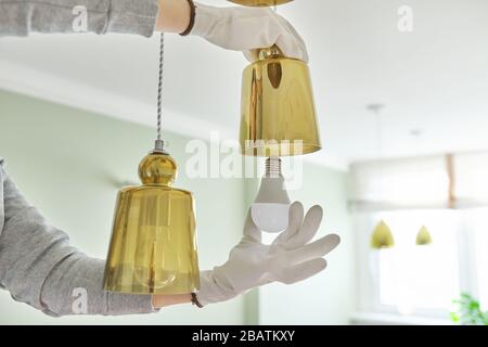 Hands installing LED bulb in lamp, chandelier. Stock Photo