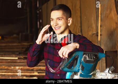 Workman at the sawmill. Young hardworking man Stock Photo