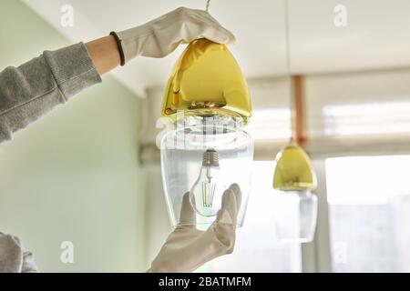 Hands installing LED bulb in lamp, chandelier. Stock Photo