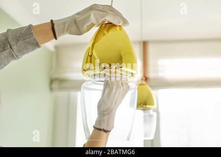 Hands installing LED bulb in lamp, chandelier. Stock Photo