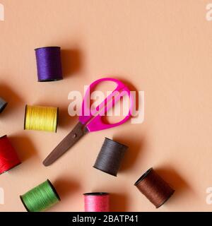 Creative composition with spools of colored threads and scissors. Sewing accessories, tailoring set. Stock Photo