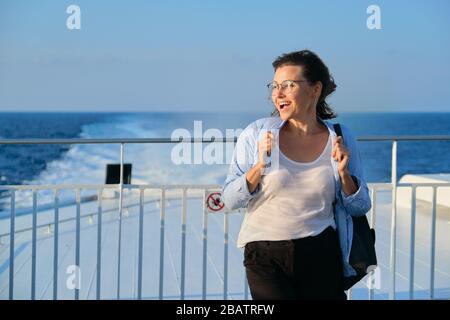 Woman on deck of ferry, female standing in strong wind, enjoying sea travel, sunset at sea, copy space Stock Photo