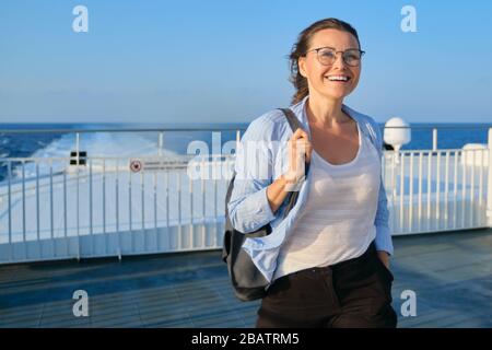 Woman on deck of ferry, female standing in strong wind, enjoying sea travel, sunset at sea, copy space Stock Photo