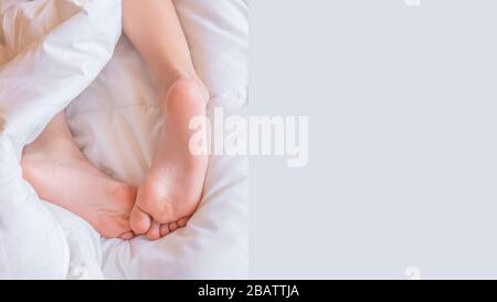 Child feet under the white blanket. Tenderness of morning baby dream Stock Photo