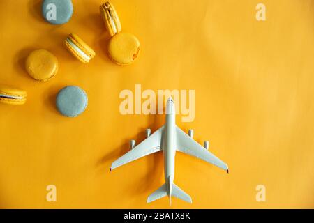 Top view of tasty orange yellow macarons and plane. Concepts ideas background on yellow paper, flatlay and copy Space Stock Photo