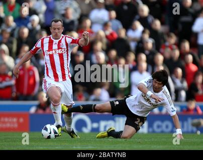 Stoke City's Charlie Adam is tackled by Swansea City's Ki Sung-Yueng Stock Photo