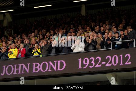 Fans observe a minutes applause in memory of former Norwich City manager John Bond before the match Stock Photo