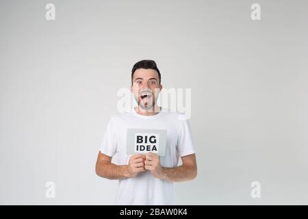 Young man isolated over background. Have a big idea. Emotional happy positive guy posing on camera alone with wonder and amazement. Lucky man. Stock Photo