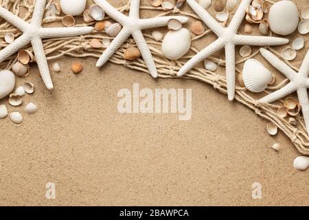 White starfishes, stones and seashells on sand background with fishing net. View from above. Flat lay Stock Photo