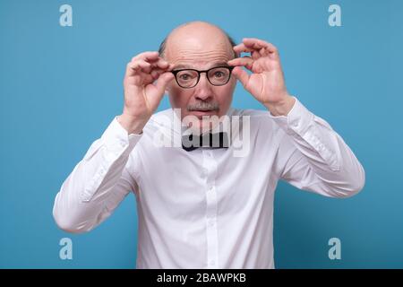 Amazed senior man looking at camera through glasses having some doubts Stock Photo