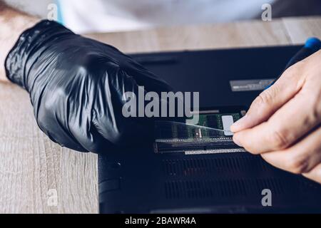 Technician installing new RAM module into the memory slot Stock Photo