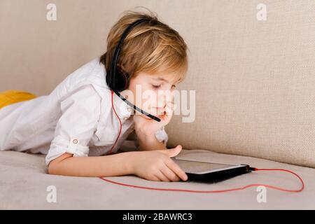 Boy in glasses on self isolation using digital tablet for his homework, for searching information on internet while school of during covid-19 lock dow Stock Photo
