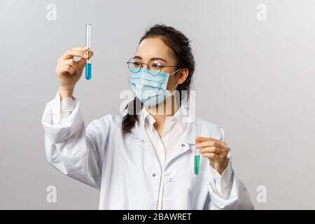 Doctors, research and covid19 concept. Portrait of young researcher infectionist, scientist looking pleased at results of tests, holding vial with Stock Photo