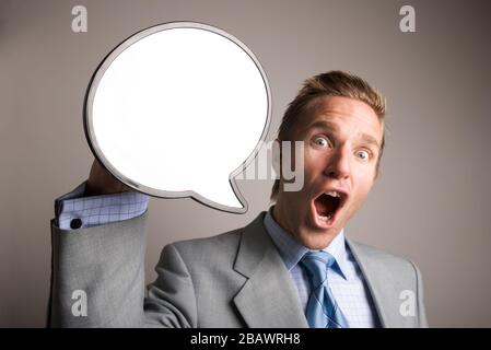 Enthusiastic businessman holding up a blank speech bubble with copy space for a message Stock Photo