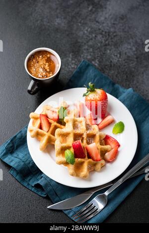 Golden belgian waffles with fresh strawberries and cup of espresso coffee. Tasty sweet breakfast food. Copy space top view Stock Photo