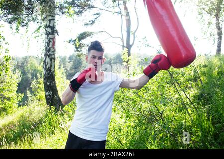 young caucasian guy boxing in gloves outside in green park, lifestyle sport people concept Stock Photo