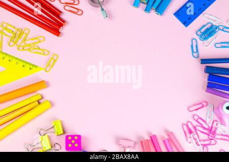 Multi-colored pencils rulers, pens, pencils and scissors and stationery stand on a pink background Stock Photo