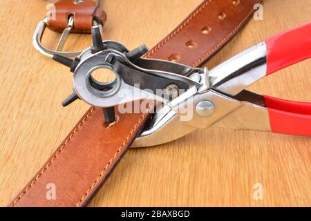 Leather punch tool and leather belth on wooden background in working position Stock Photo