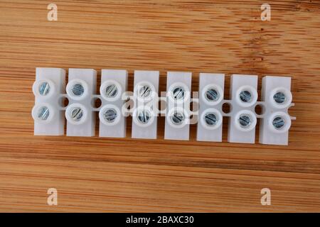 White plastic electrical connectors, terminal blocks clamps for electric cables on wooden background Stock Photo