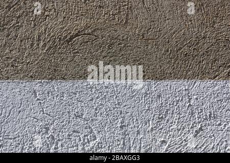 Image of a concrete wall that has part of it painted white dividing the image into two different colored textures Stock Photo