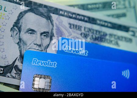 Stone / United Kingdom - March 29 2020: Revolut cards placed on top of dollar notes. Concept photo for revolut bank expansion to American market. Stock Photo