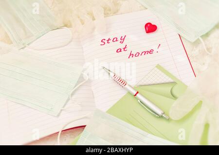 Stay at home, text of motivational words in school notebook, on background of medical masks and protective latex medical gloves, self-isolation, stay Stock Photo