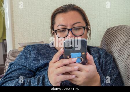A lady using a mobile phone at home. Stock Photo