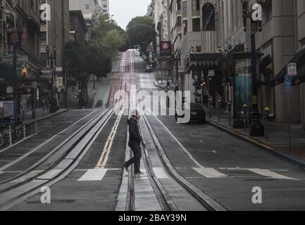 San Francisco, United States. 29th Mar, 2020. A pedestrian crosses Powell Street in San Francisco on Sunday, March 29, 2020. The city has shut down Cable Car service and ordered its citzens to shelter in place because of Coronavirus. Photo by Terry Schmitt/UPI Credit: UPI/Alamy Live News Stock Photo