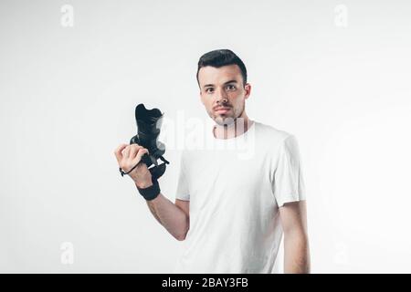 Amazed emotional young professional photographer isolated over background. Hold camera device in hand and look straoght. Stock Photo