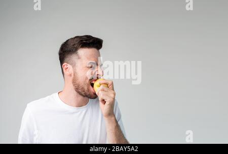 A man bites an apple and he likes it. He smiles. Stock Photo